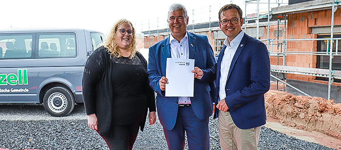 Karolina Enders (von links), Timo Zentgraf und Frederik Schmitt bei der Bescheidübergabe vor der Kita Zauberwald in Künzell-Bachrain. Foto: Lisa Laibach