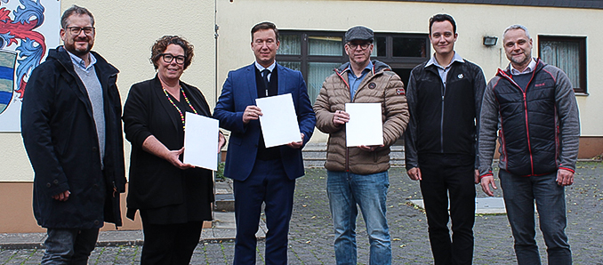 Bei der Übergabe der Förderbescheide aus Mitteln der hessischen Dorferneuerung für die Stadt Schlüchtern (von links): Johannes Michel (Leiter Abteilung Ländlicher Raum beim Main-Kinzig-Kreis), Erste Kreisbeigeordnete Susanne Simmler, Bürgermeister Matthias Möller, Ortsvorsteher Steffen Auth, Moritz Föller (Stadt Schlüchtern) und Thomas Rau (Stadt Schlüchtern). Im Hintergrund das in die Jahre gekommene Dorfgemeinschaftshaus in Elm, das durch einen Neubau ersetzt werden soll.
