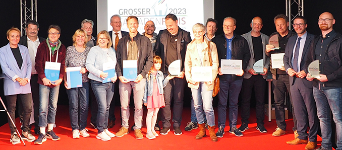 Landrat Thorsten Stolz (Zweiter von rechts) und Obermeisterin Esther Hummel, (links) verliehen den „Großen Fassadenpreis 2023“ auf der Messe Wächtersbach. Zu den Gästen zählte auch Wächtersbachs Bürgermeister Andreas Weiher (Siebter von links).