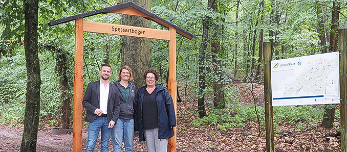 Erste Kreisbeigeordnete Susanne Simmler (rechts), Annika Ludwig, Geschäftsführerin des Zweckverbandes Naturpark Hessischer Spessart e.V, und Langenselbolds Bürgermeister Timo Greuel präsentieren den neuen Spessartbogen-Torbogen am Wanderparkplatz „Buchberg“ in Langenselbold.